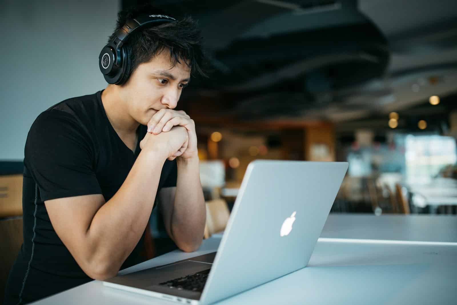 Is ADHD a Learning Disability man wearing headphones while sitting on chair in front of MacBook - ADHD coach UK