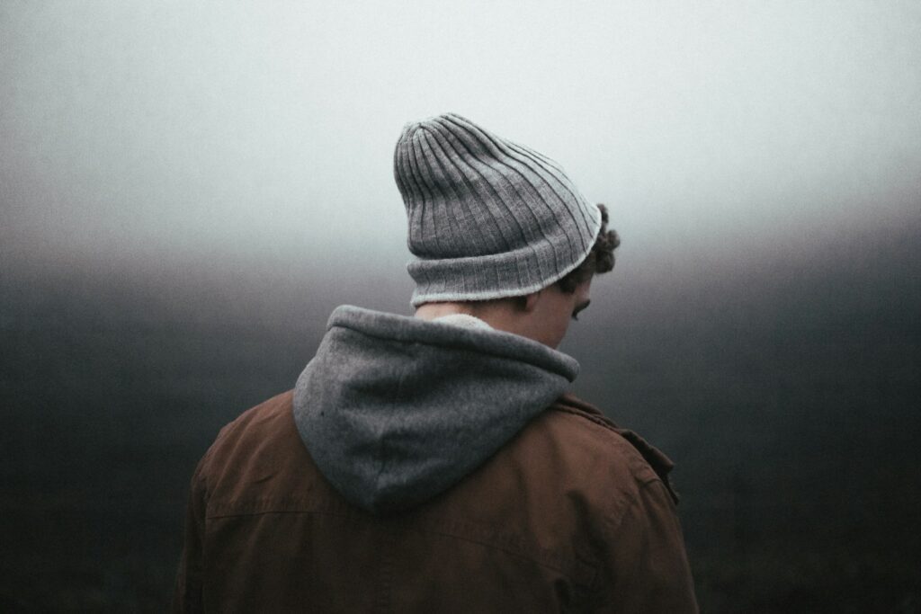 man wearing knit cap on grey background - ADHD meltdown vs autism meltdown
