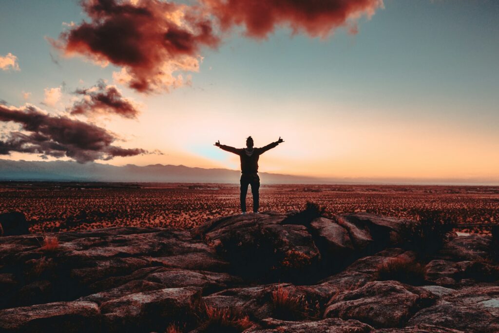 person standing on rock raising both hands - adhd success stories